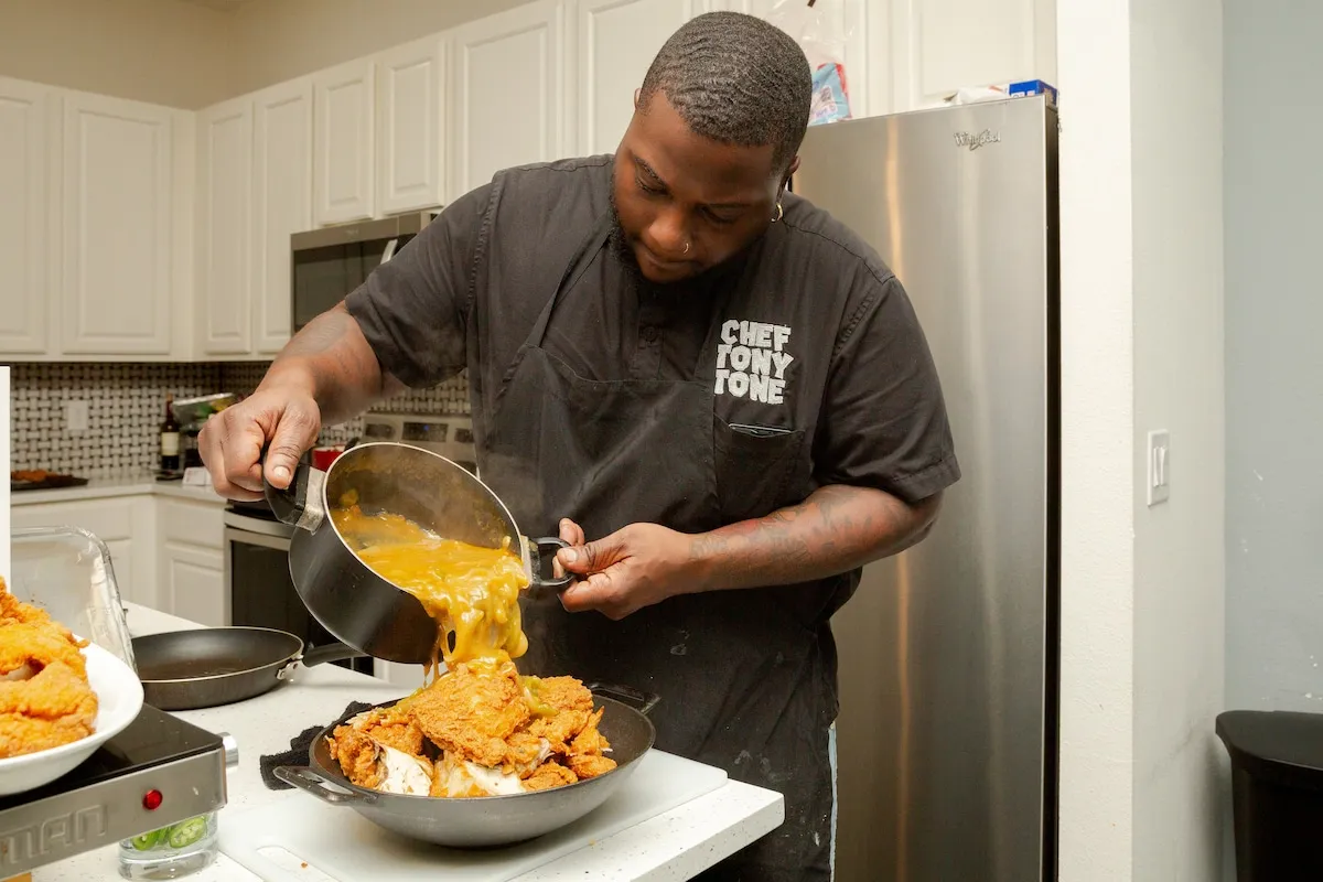 Tony pouring cheese sauce into a pan of mac and cheese